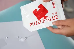 Nahaufnahme von 60 ml transparentem Flüssig-Puzzlerkleber beim Auftragen auf Papier