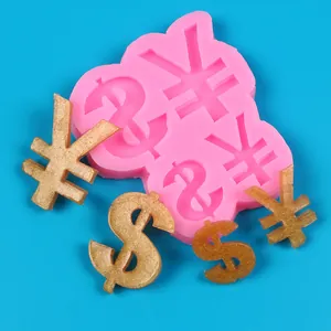 Close-up detail of a pink silicone mold showing finished golden currency symbol resin pieces