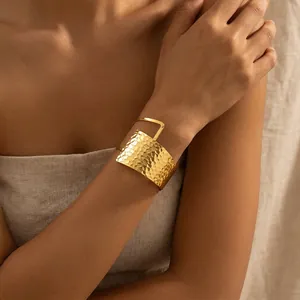 Detalle en primer plano de un brazalete dorado martillado estilo vintage en una muñeca