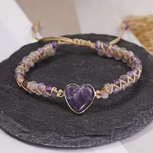 Vista detallada de una pulsera de yoga trenzada a mano con corazón de piedra púrpura.