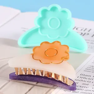 Macro view of handmade flower hair clip beside its mint green silicone mold for DIY crafts