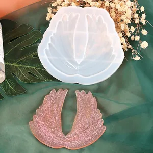 Detail view of a wing-shaped silicone mold shown with a pink glitter resin outcome piece.