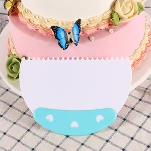 Detalle de raspador de plástico para tartas con borde dentado y mango azul de corazones
