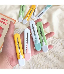 Detail shot of mini candy-colored utility knives held in hand for size comparison.