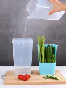 Détail montrant le versement d'eau dans un bac de conservation transparent pour légumes.