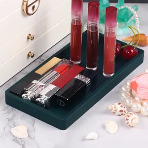 Dark green silicone organizer tray holding cosmetics and jewelry in a marble setup