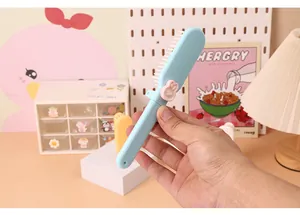 Hand-held view of a cute light blue foldable mini hair comb with rabbit detail
