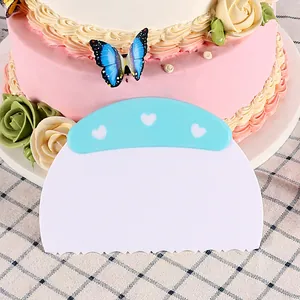 Primer plano de un raspador de pasteles de plástico blanco con mango de corazones azules.