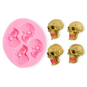 Detail of a pink silicone skull mold alongside four finished golden skull figurines.