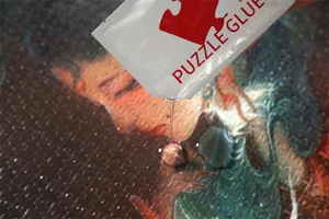 Nahaufnahme von transparentem PVA-Puzzle-Kleber, der auf ein fertiges Puzzle gegossen wird