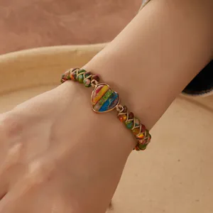 Primer plano de una pulsera de yoga tejida a mano con una piedra imperial en forma de corazón