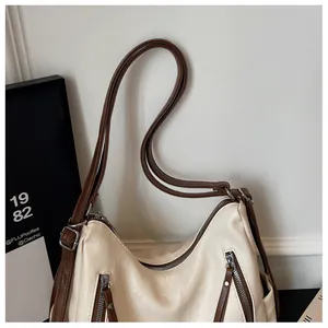 Detail shot of a cream underarm tote bag with brown straps and zipper accents