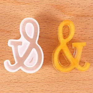Macro view of ampersand symbol silicone mold and yellow glitter resin craft detail.