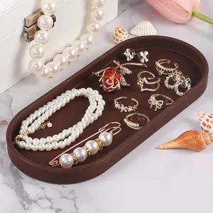 Elegant brown oval silicone jewelry organizer tray with pearls and gold rings..