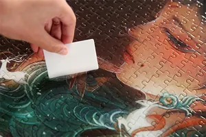 Detailansicht von klarem Puzzle-Kleber, der mit einem weißen Schaber aufgetragen wird.