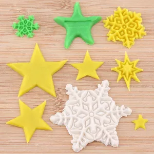 Detailopname van gele en witte ster- en sneeuwvlok fondantvormen op houten bord