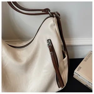 Detailed close-up of cream hobo bag showing zipper pocket and soft texture.