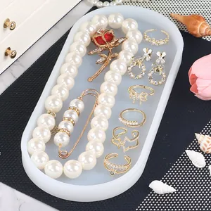 Elegant white oval silicone jewelry tray organizer displaying pearl necklace and rings