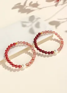 Close-up of red cinnabar and agate beaded bracelets with white pearl detail