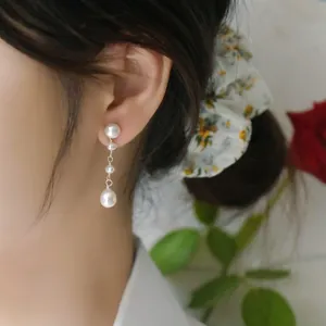 Close-up of elegant long freshwater pearl drop earrings worn by a model for a vintage look