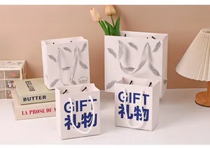 Set of elegant white paper gift bags with feather patterns and 'GIFT' text prints
