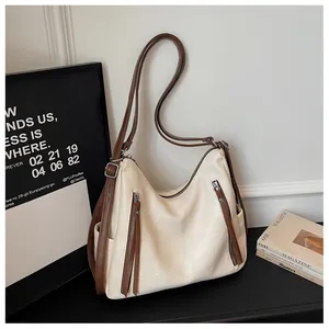 Detail view of stylish cream underarm tote bag with brown straps on a minimal scene