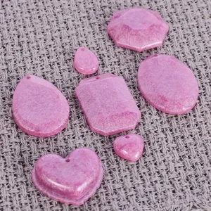 Détail de pendentifs en résine rose pailletée DIY en forme de cœur et formes géométriques