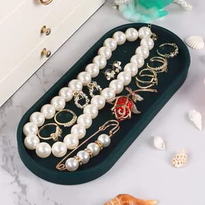 Dark green silicone tray organizing various elegant jewelry pieces on a marble surface.