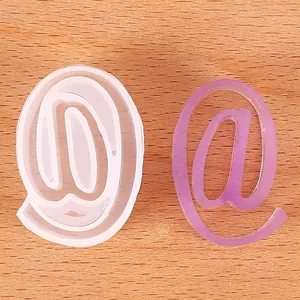 Detail view of a DIY @ symbol silicone mold with a purple glitter resin cast piece.
