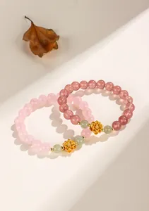 Detail of pink strawberry quartz bracelet with gold lotus charm and green jade beads