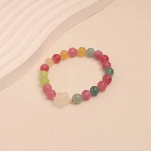Close-up of colorful tourmaline beaded bracelet with a white carved flower charm