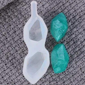Close-up of diamond crystal resin mold with green finished pendants on grey knit