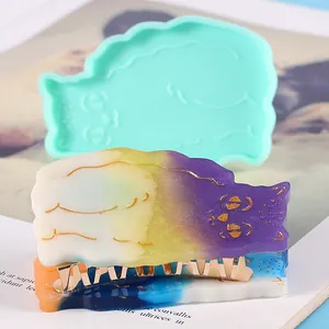 Detailed macro view showing a turquoise DIY cat-shaped silicone mold and a colorful resin clip