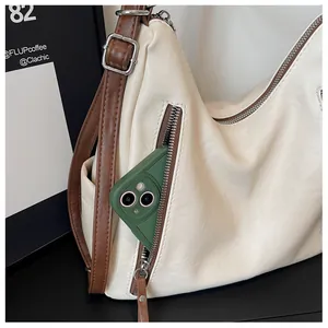 Close-up detail of the side zipper pocket on a beige leather underarm bag for women