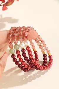 Detailed view of stacked beaded bracelets featuring cinnabar, jade, and shell pearls.