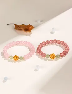 Close-up of pink strawberry crystal bracelets with gold lotus charms and jade beads