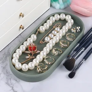 Detailed view of a green silicone tray organizing pearl necklaces and gold rings