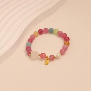 Close-up of colorful tourmaline crystal beaded bracelet with a golden Fu tag charm