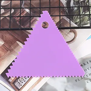 Detail view of a purple plastic triangular scraper with serrated edges for cake decorating.