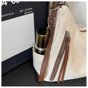 Close-up detail of cream leather underarm bag showing side pocket storage capacity.