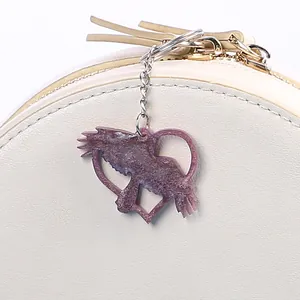 Close-up of a purple glitter heart angel resin pendant hanging on a bag zipper charm