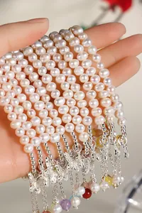 Detailed view of white freshwater pearl bracelets with butterfly charms and colorful gems.