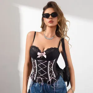Dettaglio del bustino in pizzo nero con fiocchi di nastro rosa e ciondolo a croce