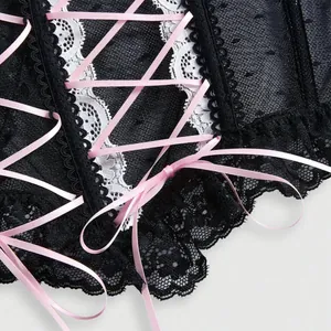 Vista dettagliata del corsetto in pizzo nero con allacciatura in nastro rosa e fiocchi