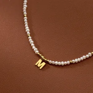 Macro detail shot of a vintage freshwater rice pearl necklace with gold M initial pendant