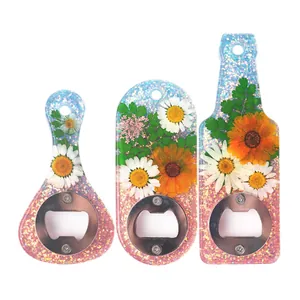 Vista dettagliata di tre apribottiglie in resina con fiori secchi veri e glitter