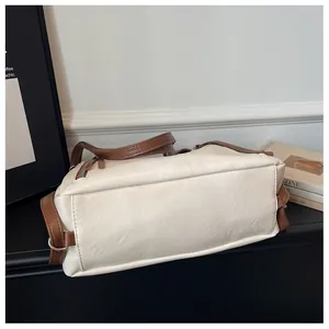 Detailed bottom view of a large capacity cream and brown leather underarm tote bag