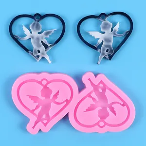 Heart-shaped Cupid angel silicone mold with finished resin pendants on blue background