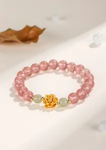 Macro view of strawberry quartz bracelet featuring a golden lotus and green jade beads