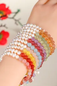 Close-up of layered freshwater pearl and multi-color gemstone bracelets on wrist